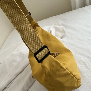 Detailed close-up of mustard yellow nylon bag showing adjustable strap and woven texture