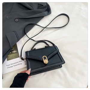 Détail du sac en cuir noir avec fermoir rotatif doré et texture élégante de haute qualité