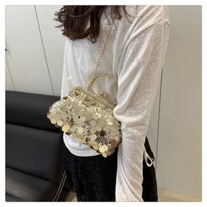 Dettaglio di una borsa da sera chic con paillettes dorate, manico in metallo e catena