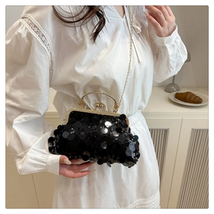 Détail du sac de soirée à paillettes noires avec bandoulière dorée sur robe blanche