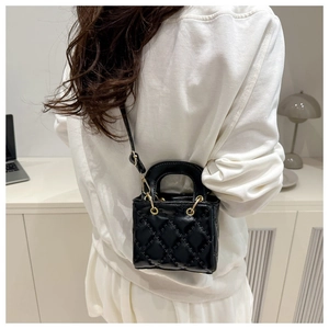 Détail du mini sac noir matelassé avec finitions dorées et poignées doubles élégantes