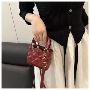 Detailed view of red patent leather mini bag with quilted stitching and gold hardware