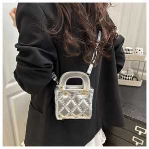Close-up of silver quilted mini crossbody bag with gold hardware worn by a model