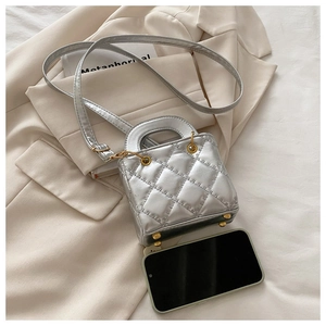 Detailopname van zilveren gewatteerde mini-handtas met gouden hardware op beige blazer