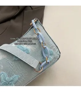 Close-up of blue lace handbag featuring 3D butterfly embroidery and gold metal hardware