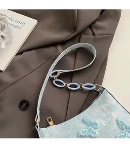 Detail of light blue lace shoulder bag with 3D butterfly appliqué and chain strap