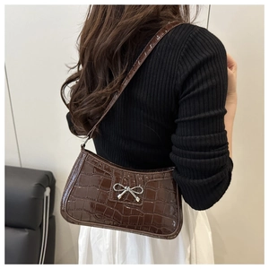Close-up of dark brown hobo bag featuring crocodile texture and silver bow detail