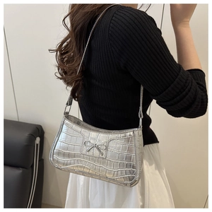 Détail du sac sous l'aisselle argenté à motif crocodile avec nœud en métal chic