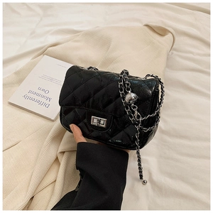 Detail of black quilted leather crossbody bag with silver chain strap and metal lock
