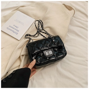 Close-up of black quilted leather crossbody bag with silver chain and twist-lock clasp