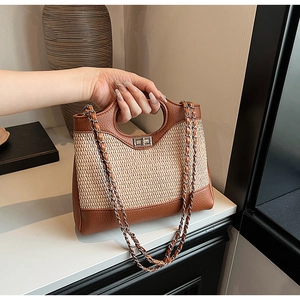 Close-up of brown leather and straw patchwork bucket bag with silver metal twist lock