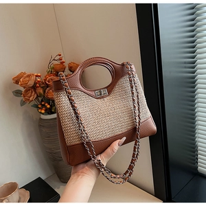 Close-up of woven straw bucket bag with brown leather trim and silver metal twist lock