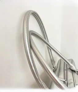 Close-up of silver PU leather handles and metallic zipper on a trendy handbag