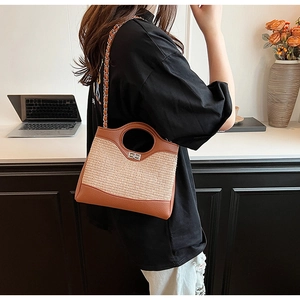Detail of a brown leather and beige woven bucket bag with chain strap and metal lock