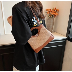 Detail of hand-woven bucket bag with brown leather trim and circular cutout handle