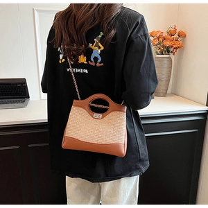 Detail of a brown leather and woven straw bucket bag worn by a model in a home setting