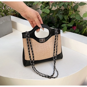 Detail of contrasting straw and leather bucket bag with silver chain and metal turn lock