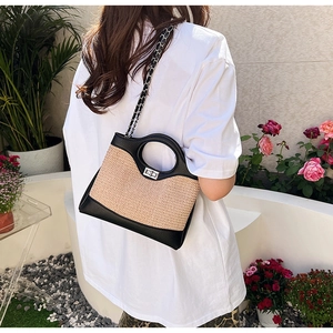 Detail of straw patchwork bucket bag with round handle and silver twist lock closure