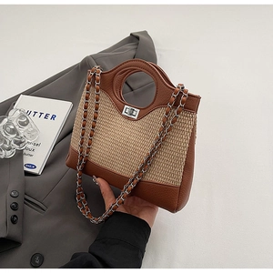 Detail of woven straw bucket bag with brown leather trim and silver metal twist lock