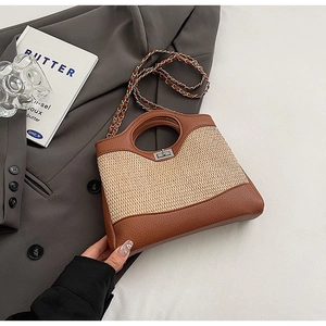 Detailed shot of beige woven straw and brown leather bucket bag with silver chain