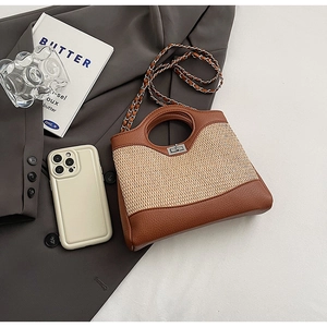 Detailed view of bucket bag featuring brown leather, woven straw panels, and chain strap