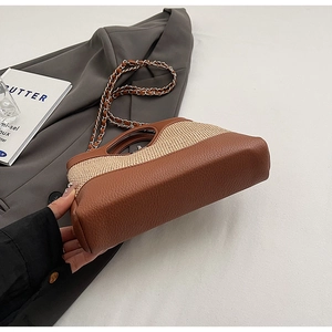Detail of the chain strap and woven straw texture on the brown bucket bag