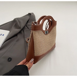 Close-up of a brown leather bucket bag with woven texture, metal lock, and chain strap