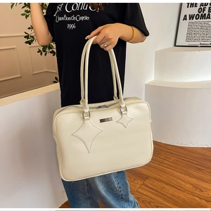 Detail of white star-patterned leather tote bag shown in a minimalist home setting