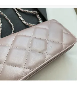 Macro detail of pink quilted leather shoulder bag with gold chain strap and metal logo