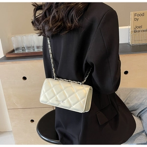 Detail of quilted rhombic pattern on beige shoulder bag with silver chain strap