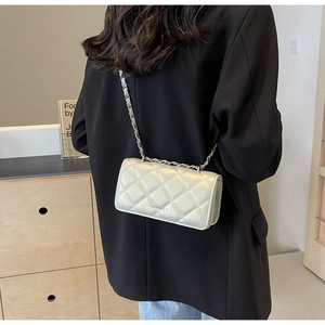 Detail of a beige quilted leather chain bag worn as a shoulder bag showing texture