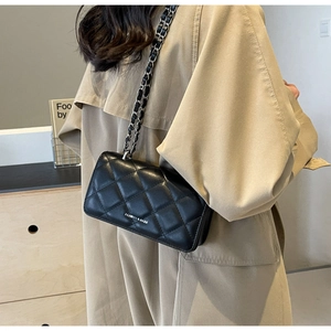 Detail view of black quilted chain bag with silver leather strap and fashion logo