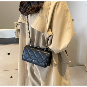 Detail of black quilted chain bag featuring elegant stitching and leather strap