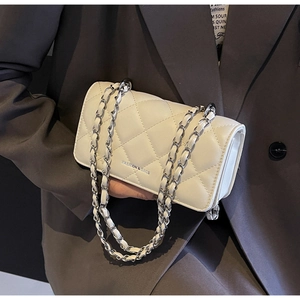 Detailed close-up of white quilted leather texture and golden metal chain strap on bag