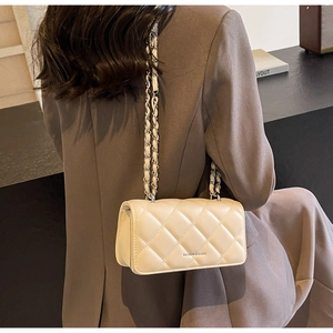 Close-up of cream quilted crossbody bag with metal chain strap and luxury leather texture