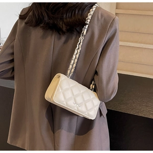 Close-up of a white quilted crossbody bag featuring a metal chain strap and sleek finish