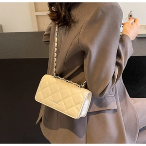 Detail of cream quilted crossbody bag with silver chain strap and leather texture