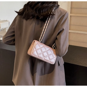 Detail of pink quilted leather crossbody bag with chain strap on model's shoulder