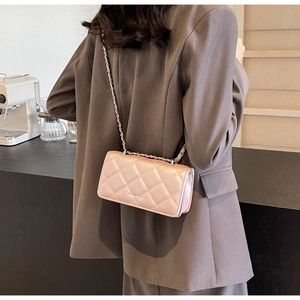 Quilted pink crossbody bag with metal chain strap shown on model in cafe setting