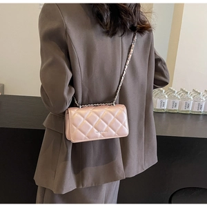 Rear view of a model wearing a pink quilted chain crossbody bag with metallic PU leather