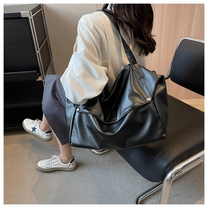 Detailed view of black textured leather tote bag with metallic stud accents and wide strap
