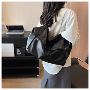 Close-up of black leather tote bag with lychee texture and silver metal buckle detail