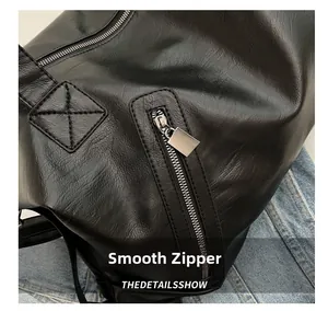 Detailed macro shot of black textured leather tote with silver zipper and reinforced stitching