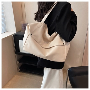 Detail of creamy white large tote bag with textured faux leather and black side buckles