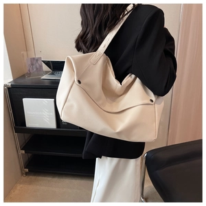 Detail of off-white tote bag with lychee texture and metallic side button on a shoulder
