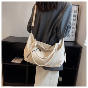 Detailed view of cream-colored large tote bag with side zipper and adjustable strap
