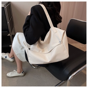 Close-up of beige lychee grain leather tote bag with metallic rivet detail on the side