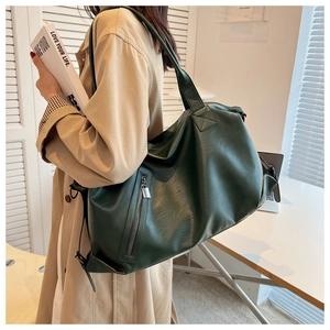 Detail of dark green tote bag with matte texture and vertical zipper on model