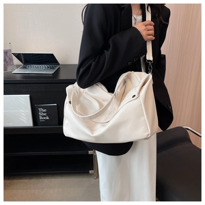 Detail of creamy white leather tote bag with wide strap and silver metal buckle