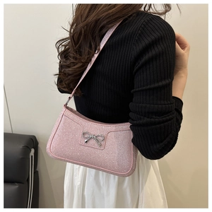 Detailed macro view of pink glitter shoulder bag featuring a silver metal bow buckle